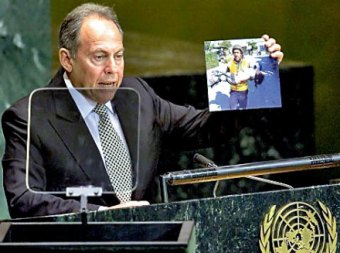 لحود يلقي كلمته في الأمم المتحدة وفي يده صورة لاحدى ضحايا مجزرة قانا