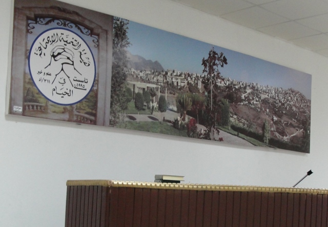 شعار "هيئة التنمية الأجتماعية في الخيام" إلى جانب صورة كبيرة لبلدة الخيام
